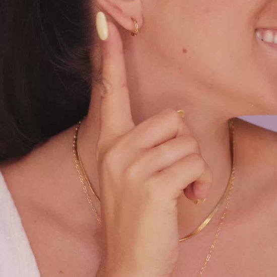 Model wearing the LucyKitty Gold Filled Twisted Hoop Earrings, Mira Herringbone Necklace, and Fayette Birthstone Necklace in April Diamond